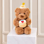 Teddy bear holding a cupcake and wearing a party hat