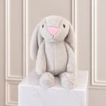 Plush gray bunny with a pink nose sitting on a marble pedestal