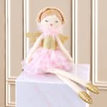 Angel doll in a pink tutu sitting on a marble box
