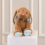 Brown plush bunny with blue ears and feet sitting on a marble pedestal