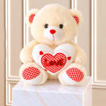 Plush teddy bear holding a heart with the word Love