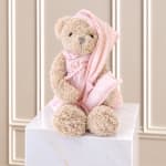 Teddy bear in pink striped pajamas sitting on a white box