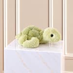 Plush turtle toy resting on a marble-patterned pedestal