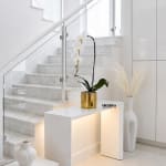 White orchid arrangement in a gold pot on a white table