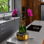 Pink orchid arrangement in a gold bowl on a kitchen island