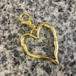 Gold heart-shaped keychain on a speckled stone surface