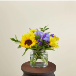 Sunflowers and purple flowers arranged in a clear glass vase