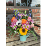 Mixed bouquet in a blue pitcher with sunflowers, roses, and daisies