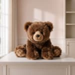 Brown teddy bear plush sitting on a white table