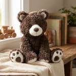 Brown teddy bear plush sitting on a knitted blanket
