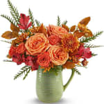 Bouquet of peach and coral roses with autumn-colored flowers in a green pitcher vase