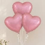 Three pink heart-shaped balloons tied with white ribbons