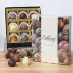 Boxed chocolate truffles and assorted truffles on a wooden surface