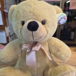 Large beige teddy bear with a satin ribbon bow