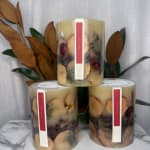 Three decorative pillar candles with dried petals and leaves