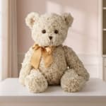 Cream teddy bear with a gold ribbon sitting on a table
