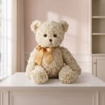 Cream teddy bear with a gold ribbon sitting on a table