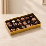 Box of assorted chocolates in a gold tray on a tabletop