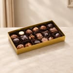 Box of assorted chocolates in a gold tray on a tabletop