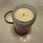 A white candle in a glass jar with its lid beside it