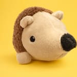 Plush hedgehog toy on a yellow background