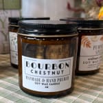 Three labeled soy wax candles in amber jars with black lids