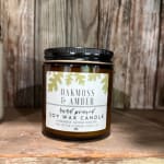 Amber jar candle labeled Oakmoss & Amber on a wooden surface