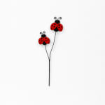 Two red and black ladybug decorations on thin stems