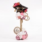 Graduation balloon display with a black cap balloon and pink and white balloons