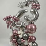 Silver and pink balloon arrangement with large number balloons and a crown topper