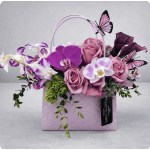 Pink and purple flowers arranged in a lavender gift bag with butterfly decorations
