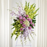 Tall floral spray with purple roses, lavender orchids, and lime-green blooms on an easel