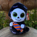 Plush skeleton toy holding a striped candy on a wooden surface
