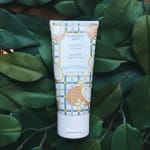Tube of coconut cream goat milk hand cream on dark green leaves