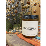Amber jar candle labeled eucalyptus on a wooden surface