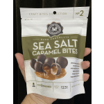 Hand holding a bag of dark chocolate sea salt caramel bites