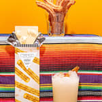 Chocolate bar and two drinks on a colorful woven cloth.