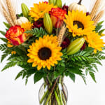 Sunflower and rose bouquet with lilies and pumpkins in a glass vase