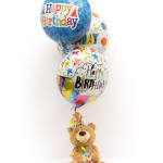 Birthday balloons with a teddy bear holding a party horn
