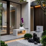 Purple orchid in a white planter on a stone bench outside a modern house