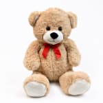 Plush teddy bear with a red ribbon bow sitting on a white background