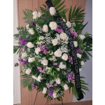 Standing funeral wreath of white and purple flowers with a black memorial ribbon
