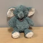 Blue plush elephant with white ears and feet, wearing a heart pendant