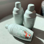 Three mint-colored bottles with floral mushroom artwork
