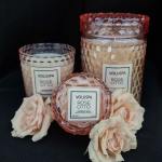 Three rose-scented candles with pale pink roses on a black background