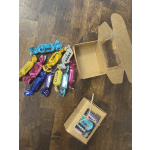 Assorted wrapped chocolates beside open cardboard gift boxes on a wooden floor