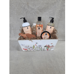 Bath gift set with orange ginger products in a floral-printed white wooden box filled with paper shred.