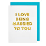 White card with gold balloon letters reading I LOVE BEING MARRIED TO YOU