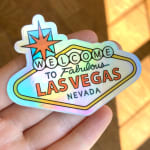 Hand holding a holographic Las Vegas sticker with text