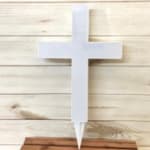 White cross-shaped grave marker on a wooden plank background
